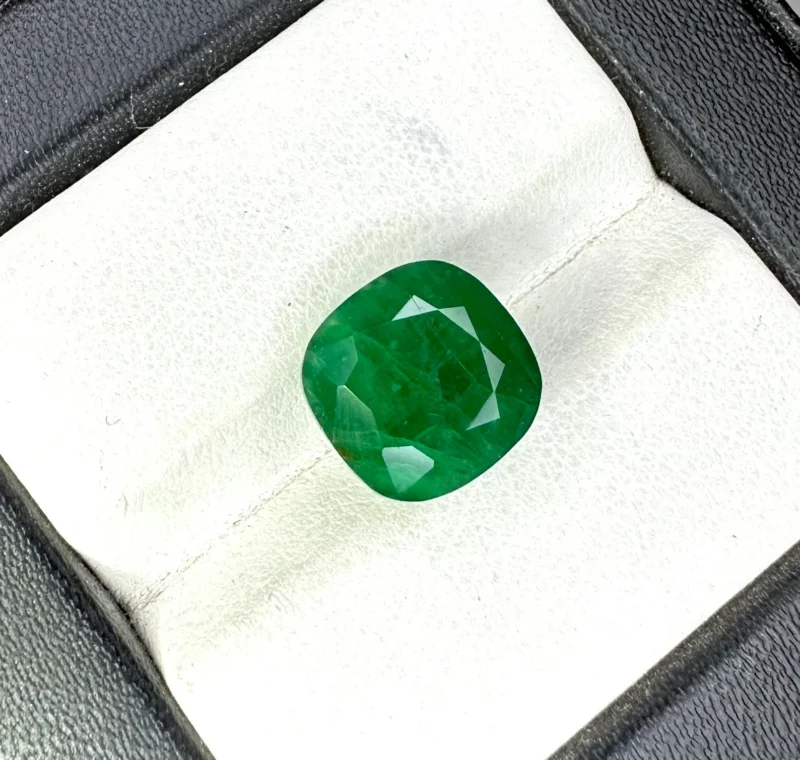 Loose Dark Green Zambian Emerald Held in Tweezers for Jewelry