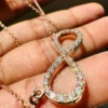 Infinity Moissanite Pendant Necklace | Rose Gold & Silver Minimalist Infinity Pendant Held Between Fingers Showing Craftsmanship