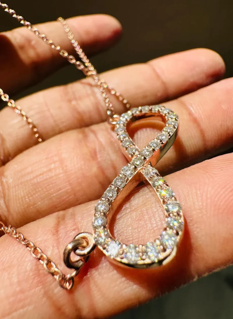 Infinity Pendant Held Between Fingers Showing Craftsmanship